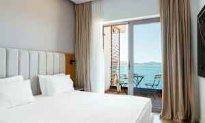 Bilde av et hotellrom med seng og en balkong med utsikt over havet. (AI-generert tekst)