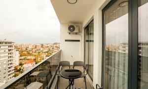 En balkong med et bord og stoler, med utsikt over en by. (AI-generert tekst)