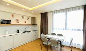 Et moderne kjøkken og spisestue med lyse møbler og store vinduer. (AI-generert tekst)