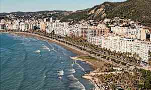 Utsikt over en by ved stranden med høye bygninger og havet i forgrunnen. (AI-generert tekst)