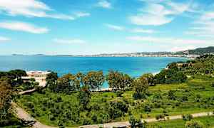 Utsikt over en kystby med sjø og grøntområder. (AI-generert tekst)