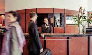 Resepsjon i en hotellobby med en gjest og en resepsjonsmedarbeider. (AI-generert tekst)