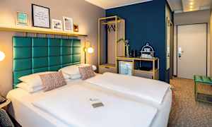 Hotellrom med en dobbeltseng, moderne interiør og et skap med kleshengere. (AI-generert tekst)