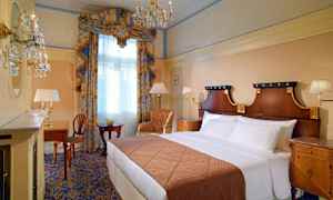 Elegant hotellrom med dobbeltseng, skrivebord og stort vindu med gardiner. (AI-generert tekst)