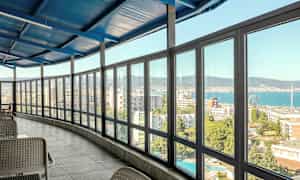 Interiør med en innglasset veranda med utsikt over en by og havet. (AI-generert tekst)