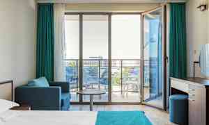 Moderne hotellrom med en seng, sittegruppe og glassdører ut til en balkong. (AI-generert tekst)