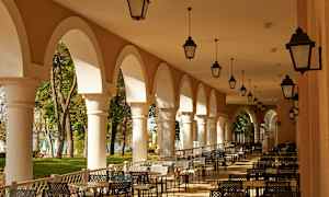 En utendørs servering med buede søyler og sittegrupper. (AI-generert tekst)