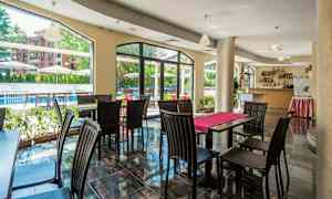 Restaurant med bord og stoler, store vinduer vender mot uteområdet. (AI-generert tekst)