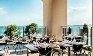 En terrasse med dekkede bord og utsikt over havet. (AI-generert tekst)