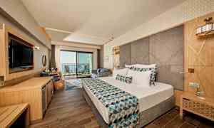 Hotellrom med moderne innredning, dobbeltseng og balkong med havutsikt. (AI-generert tekst)