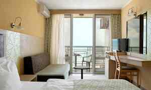 Et hotellrom med havutsikt og balkong. (AI-generert tekst)