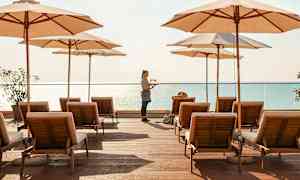 Solstoler og parasoller på en treplattform ved havet. (AI-generert tekst)