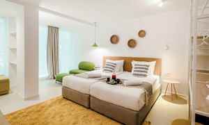 Et moderne hotellrom med to enkeltsenger, grønn sittemøbel og dekorasjoner på veggen. (AI-generert tekst)