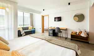 Moderne hotellrom med dobbeltseng, sofa og skrivebord. (AI-generert tekst)