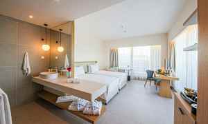 Et moderne hotellrom med to enkeltsenger, skrivebord og integrert bad med servant. (AI-generert tekst)