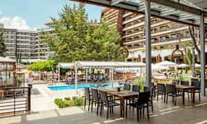 Utendørsområde ved hotell med et basseng og sitteplasser under tak. (AI-generert tekst)