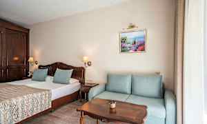 Rom med dobbeltseng, sofa, trebord og veggdekorasjon. (AI-generert tekst)