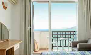 Hotellrom med åpen balkongdør og havutsikt. (AI-generert tekst)