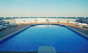 Basseng med solsenger og blå himmel. (AI-generert tekst)