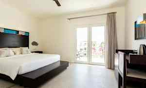 Et hotellrom med en dobbeltseng, skrivebord og balkongdører. (AI-generert tekst)