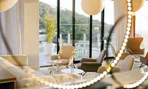 Et moderne rom med sitteplasser og sofaer, store vinduer som vender mot en terrasse. (AI-generert tekst)