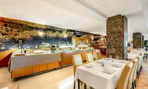 En restaurantinteriør med dekkede bord og en buffet oppstilt i bakgrunnen. (AI-generert tekst)