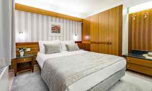 Et hotellrom med en oppredd seng, treinteriør og veggkunst. (AI-generert tekst)