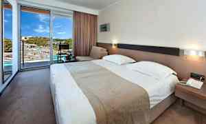 Et hotellrom med en dobbeltseng, sitteområde og en terrasse med utsikt. (AI-generert tekst)