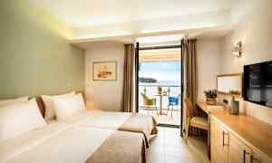 Et hotellrom med to enkeltsenger, en balkong med havutsikt og en sittegruppe. (AI-generert tekst)