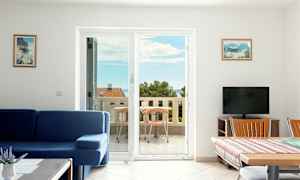 Stue med blå sofa og spisebord ved siden av en balkong med havutsikt. (AI-generert tekst)