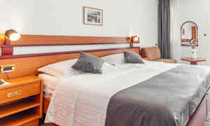 Hotellrom med stor seng, sidebord og dekorasjoner. (AI-generert tekst)