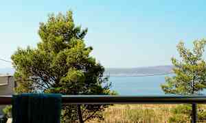 Utsikt fra en balkong med trær og havet i bakgrunnen. (AI-generert tekst)