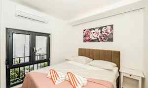 Et soverom med en dobbeltseng, dekorert med et maleri av blomster på veggen over sengen. (AI-generert tekst)