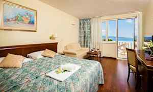 Hotellrom med dobbeltseng og balkong med havutsikt. (AI-generert tekst)