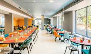 Spisesal med fargerike stoler og bord dekket for servering. (AI-generert tekst)