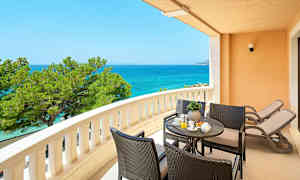 En balkong med utsikt over havet, sittegruppe og to solstoler. (AI-generert tekst)