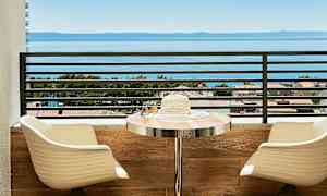 Utsikt over havet fra en balkong med sitteplasser og et bord. (AI-generert tekst)