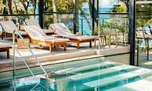 Solstoler ved et basseng med utsikt over havet. (AI-generert tekst)