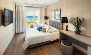 Hotellrom med dobbeltseng og utsikt over havet. (AI-generert tekst)