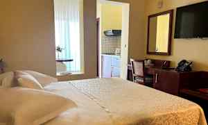 Bilde av et hotellrom med en dobbeltseng, skrivebord og en kjøkkenkrok. (AI-generert tekst)