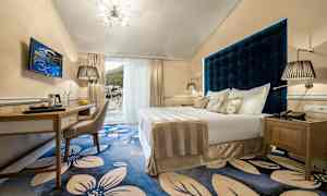 Hotellrom med dobbeltseng og blå blomstret gulv. (AI-generert tekst)