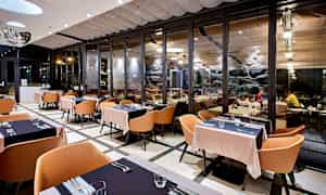 Restaurant med moderne interiør og store glasspartier. (AI-generert tekst)