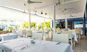 Uteservering med bord dekket med hvite duker. (AI-generert tekst)