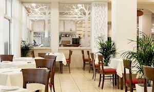 En restaurant med bord og stoler, dekorert med planter og en glassvegg med et tredesignmotiv. (AI-generert tekst)