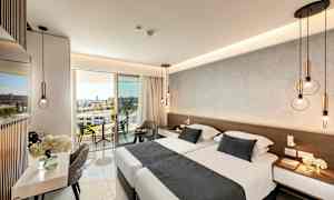 Moderne innredet hotellrom med dobbeltseng, sittemøbler og en balkong med utsikt. (AI-generert tekst)