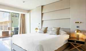 Moderne hotellrom med stor seng, elegant innredning og utsikt mot en terrasse. (AI-generert tekst)