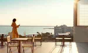 Person på en terrasse med utsikt over havet. (AI-generert tekst)