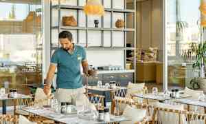 Et caféområde med bord, stoler og et åpent serveringsområde. (AI-generert tekst)