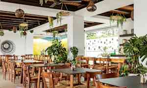 Restaurant med trebord og stoler, dekorert med grønne planter. (AI-generert tekst)