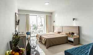 Et hotellrom med dobbeltseng, sitteområde og en terrasse utenfor. (AI-generert tekst)